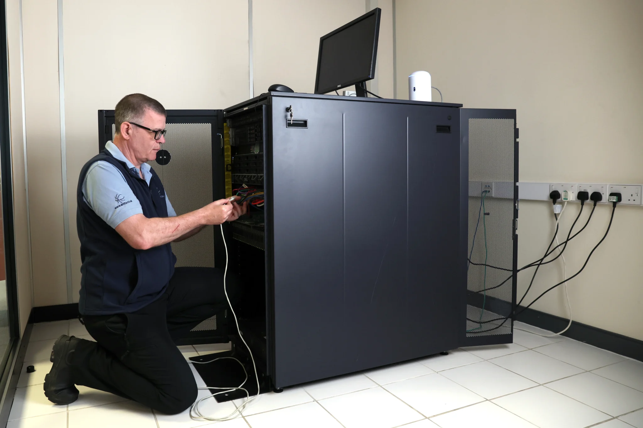 a man fixing wires in server rack