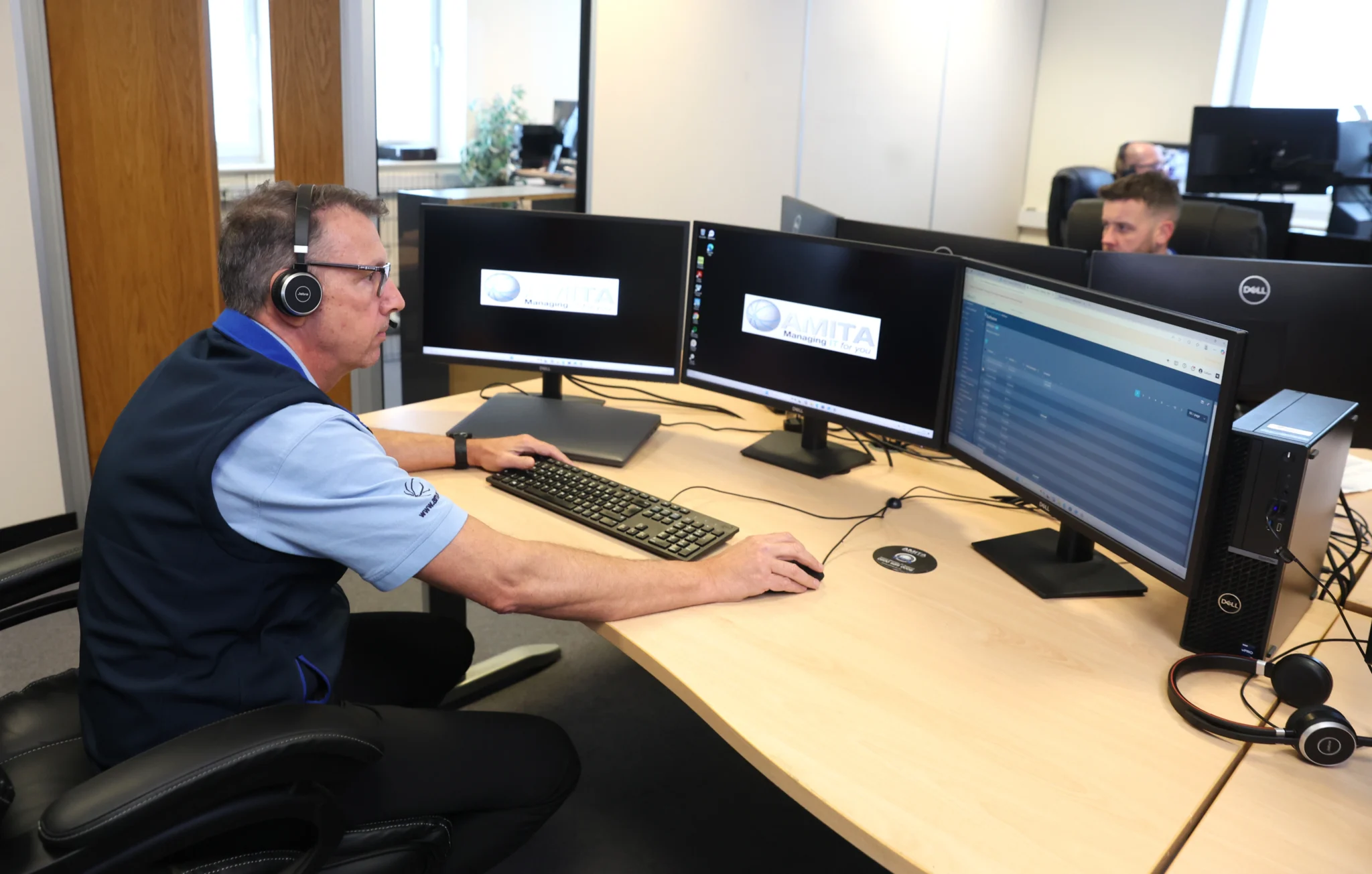 a man working in front of three monitors